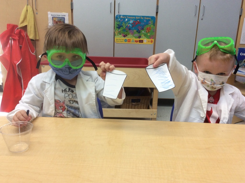 Two students show their drawings of their experiment results