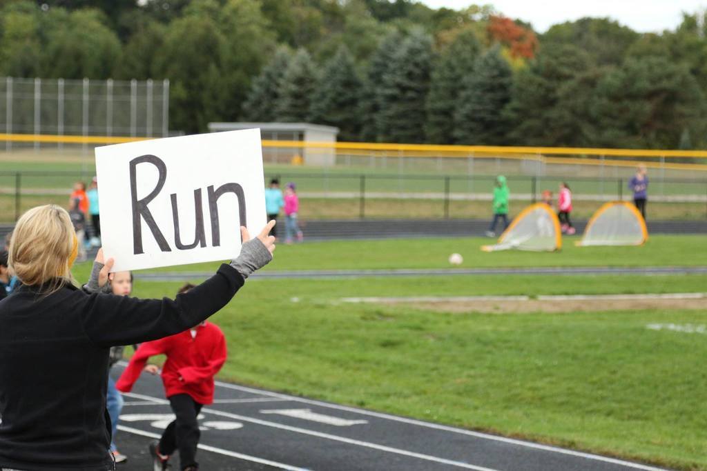 Student race by adult holding sign saying, "Run"