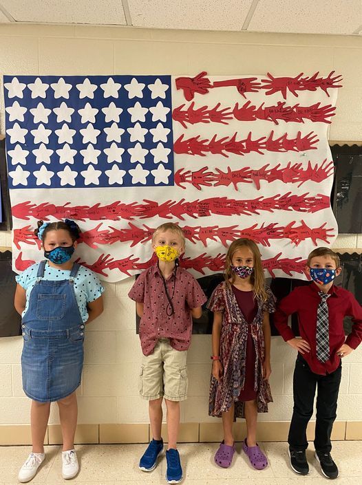 Four student pose in front of the US flag they made