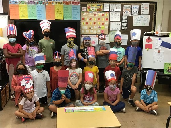 Students pose in their USA themed hats made of construction paper