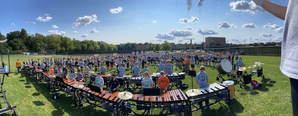 Panorama view of marching band practicing on field in formation
