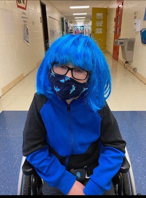 Student with blue wig and shark mask poses in hallway