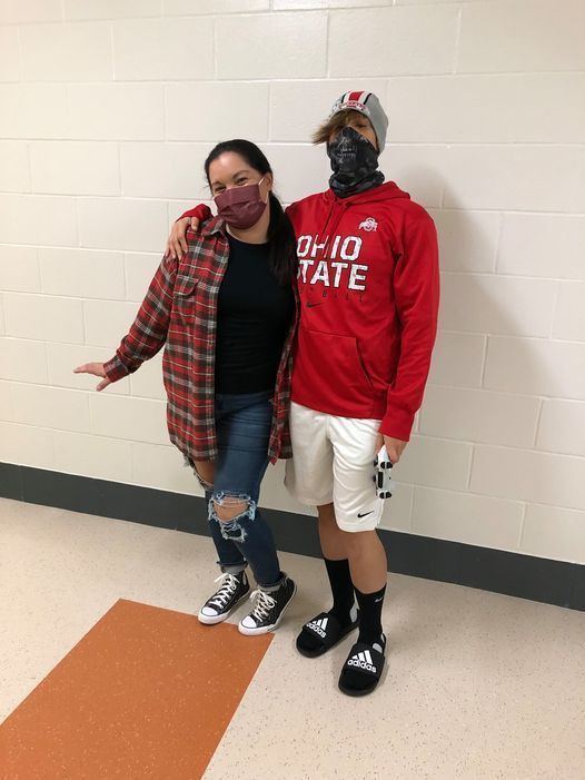 Two teachers dressed as students pose in hallway