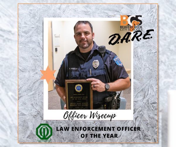 Police officer poses with plaque with text "Officer Wisecup - Law Enforcement Officer of the Year"
