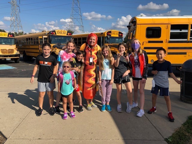 Group of elementary students pose with teacher in hot dog costume