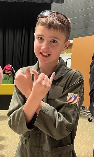 Boy in flight suit giving Fly Ok sign